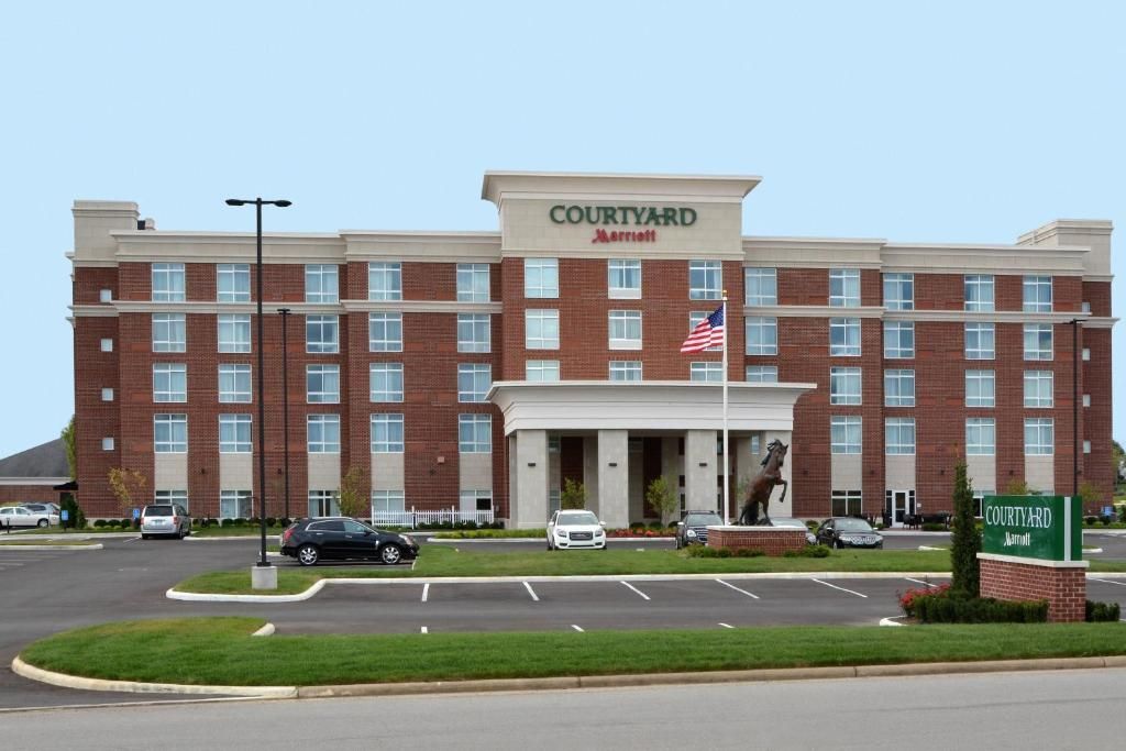 Courtyard by Marriott hotel building with brick facade and green lawn. Parking lot in foreground.