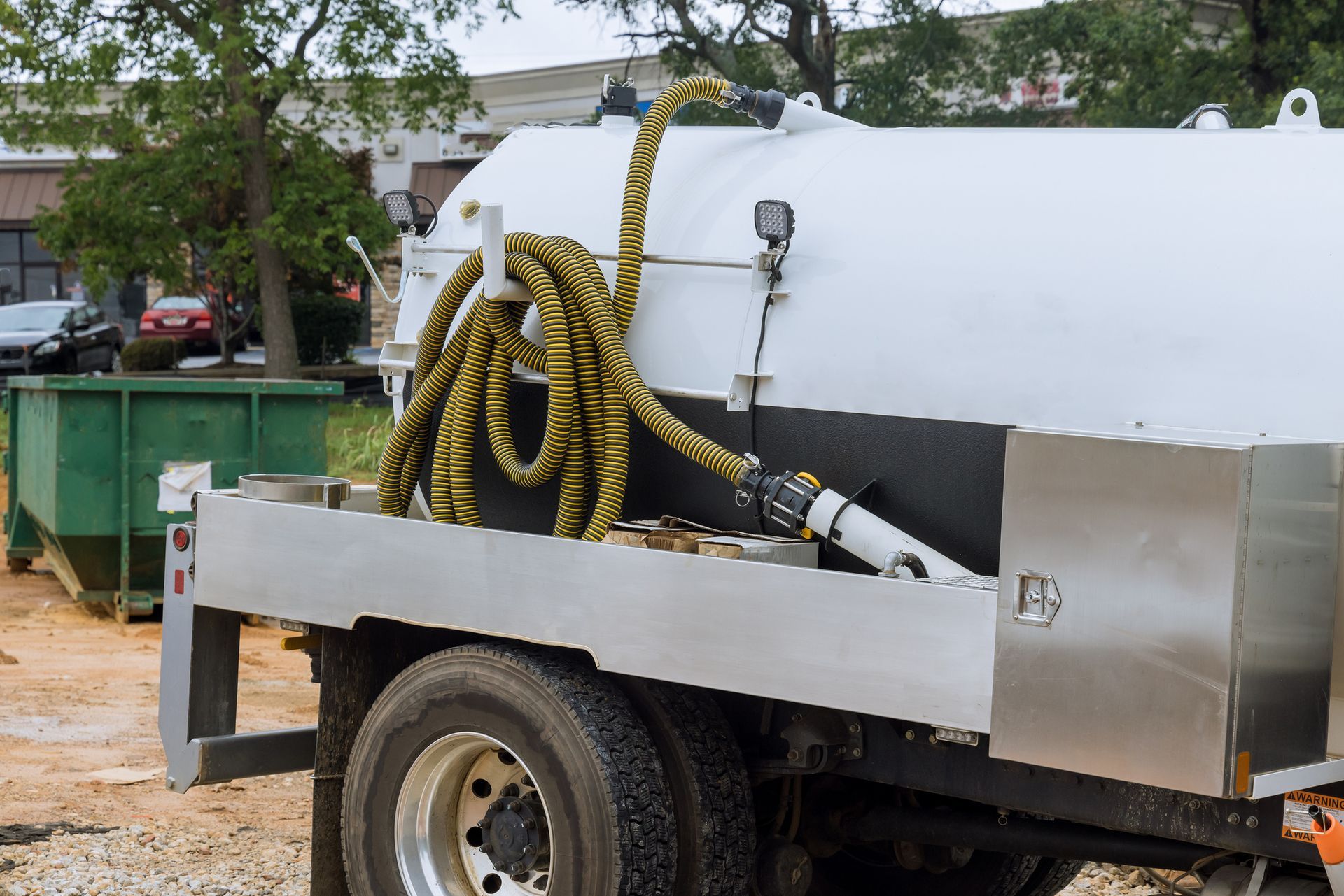 Septic truck with hoses at construction site.