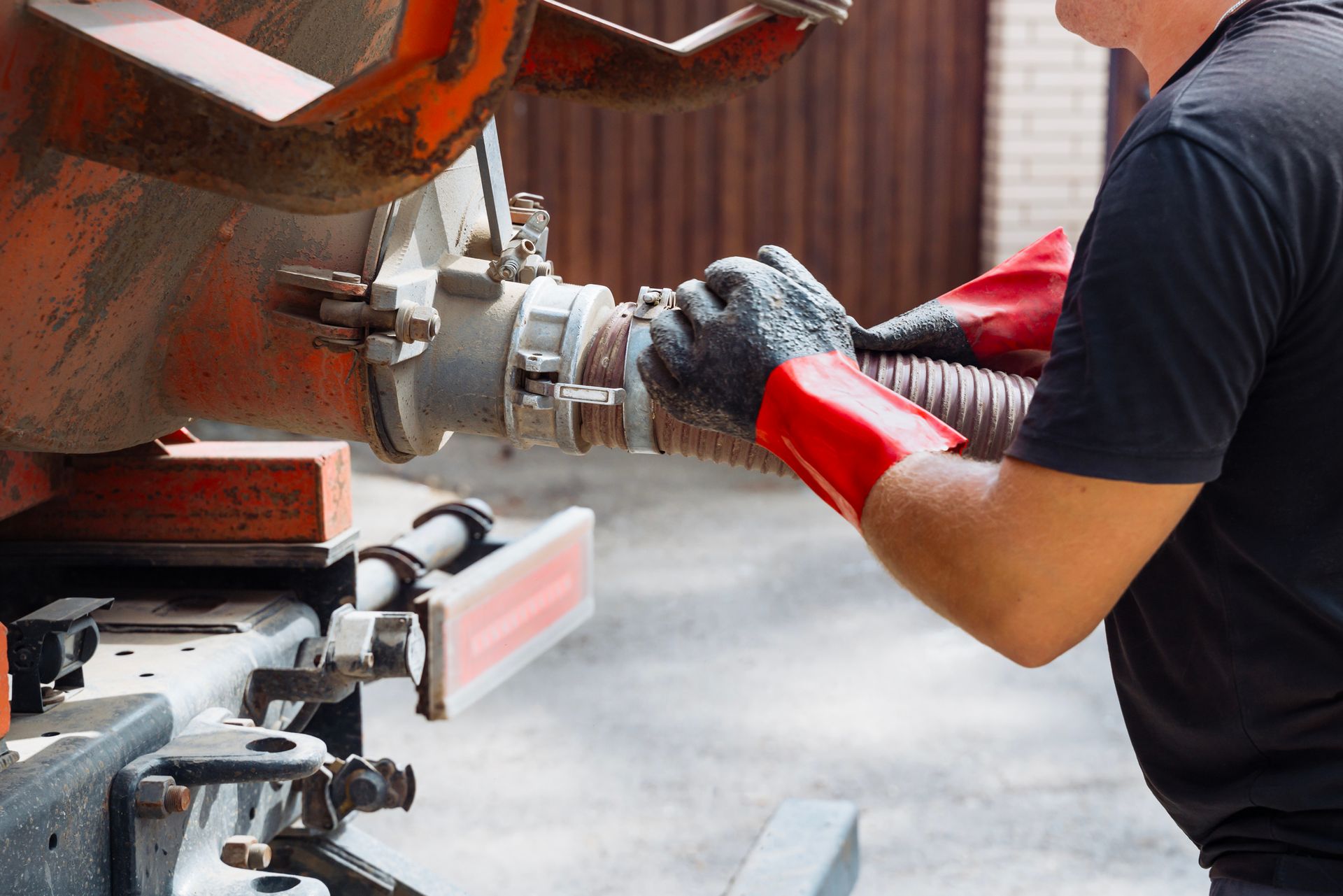 Worker in gloves connecting hose to industrial machine.