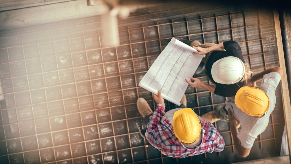 Men Looking At A Blueprint — Carlsbad, NM — ENM Construction Management Ltd Men Looking At A Blueprint — Carlsbad, NM — ENM Construction Management Ltd