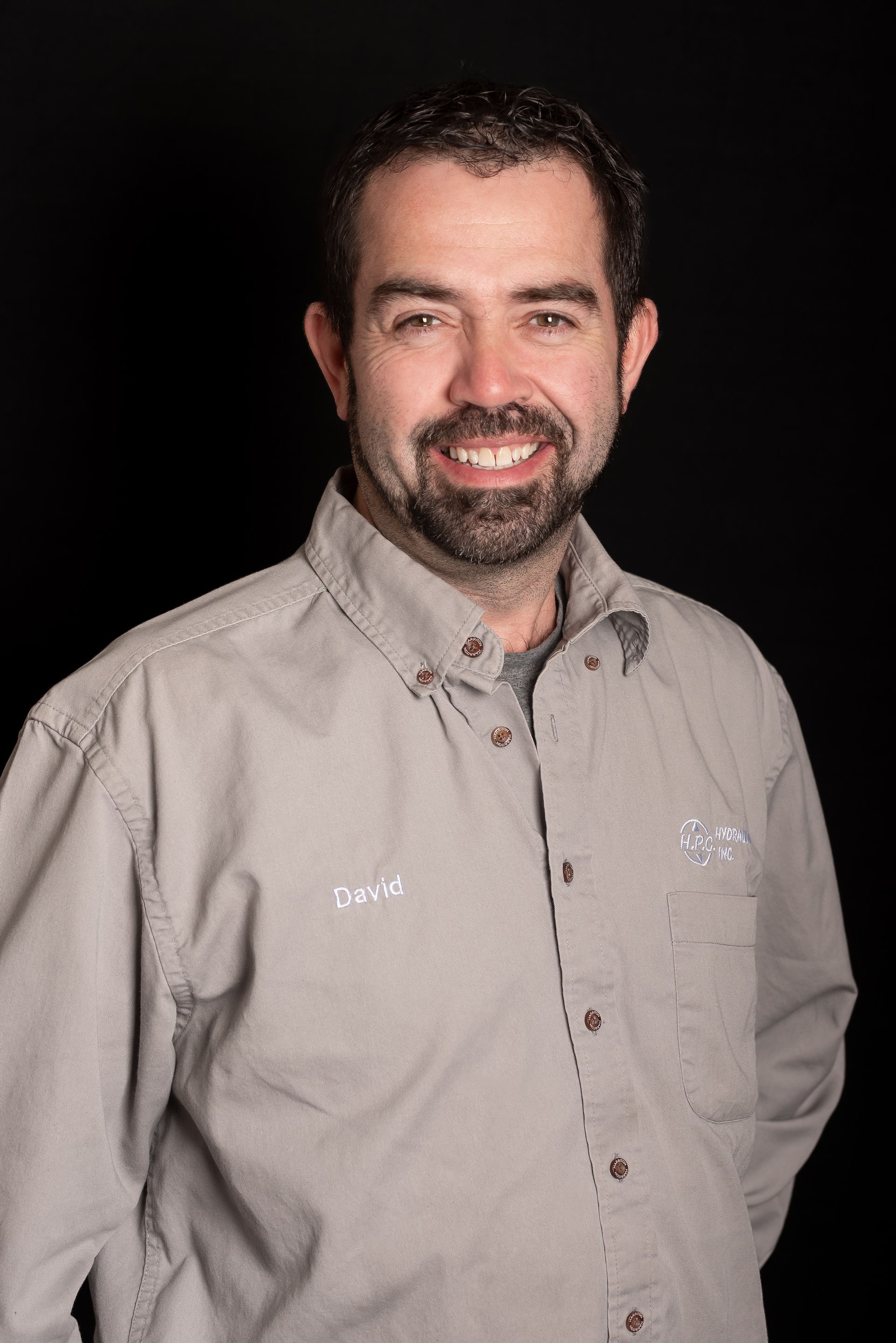 Smiling man in a light grey button-down shirt with