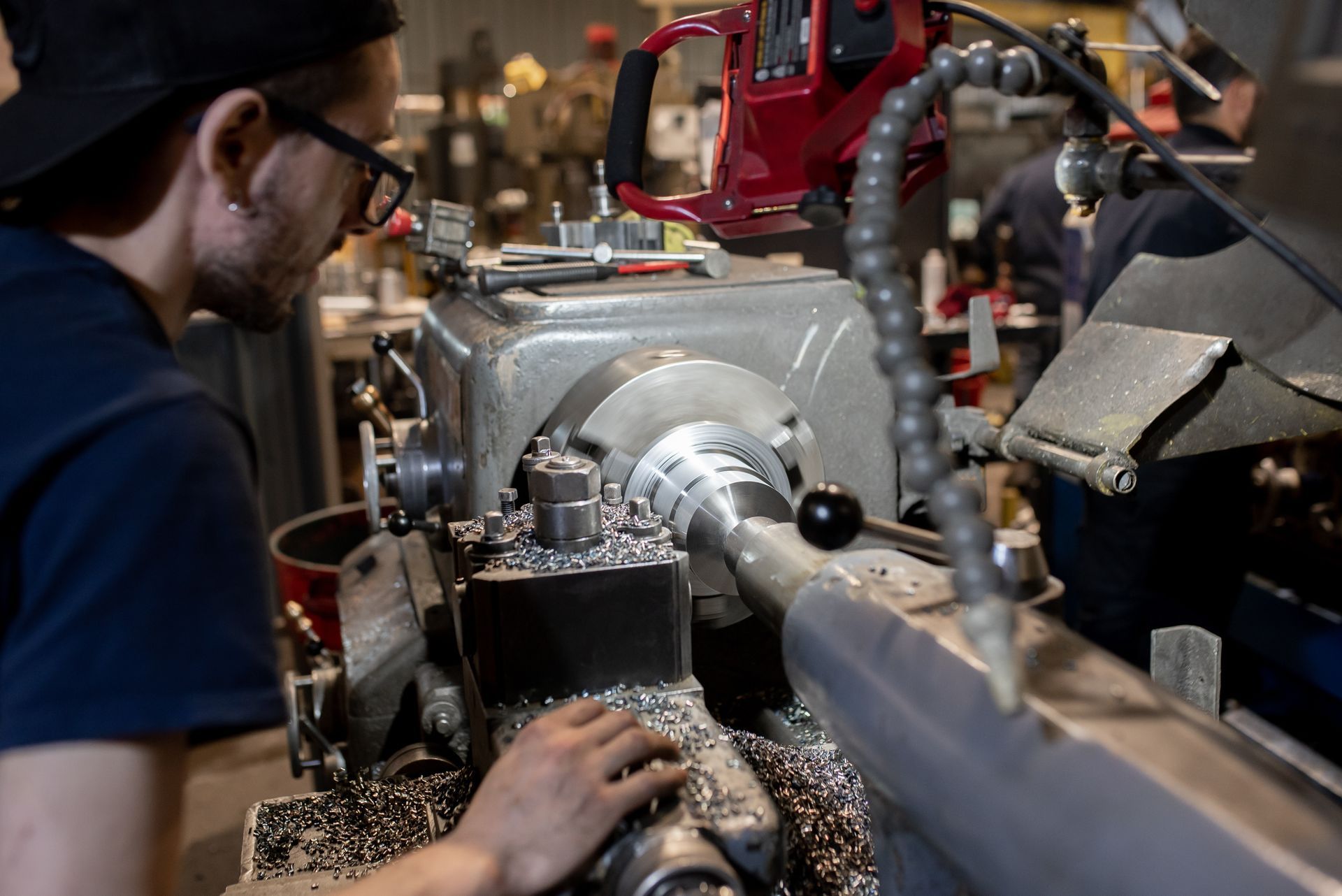 Homme utilisant un tour dans un atelier, copeaux visibles.