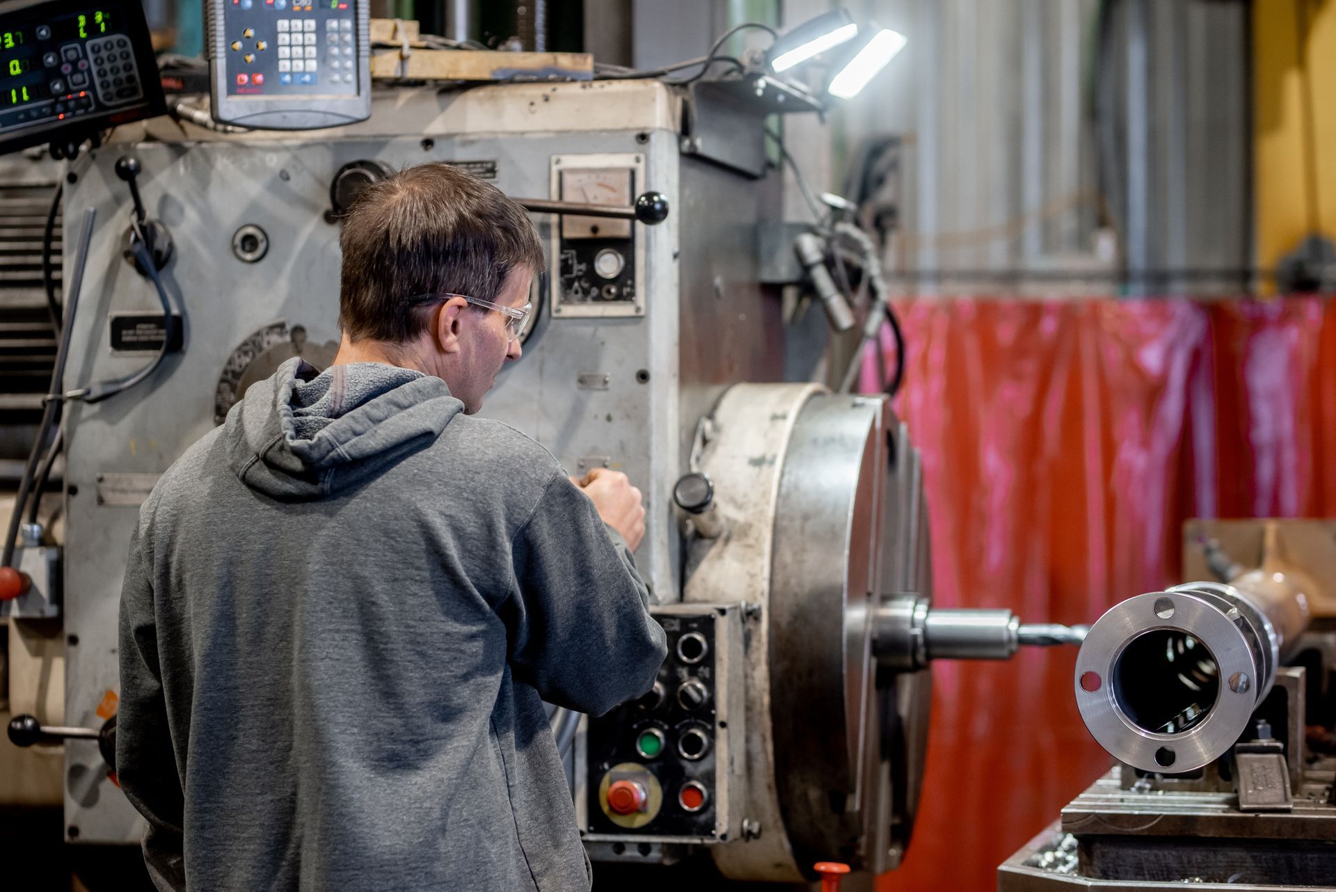 Un homme utilise un grand tour à métaux dans un atelier. Il est concentré sur sa tâche.