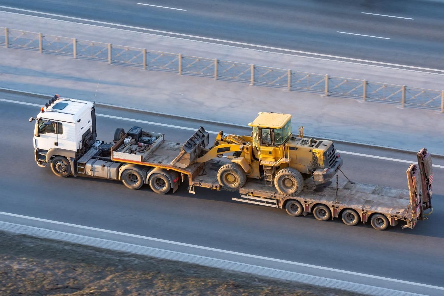 A Truck is Carrying a Bulldozer on a Trailer on a Highway — DJ's Tilt Tray Service in Sawtell, NSW
