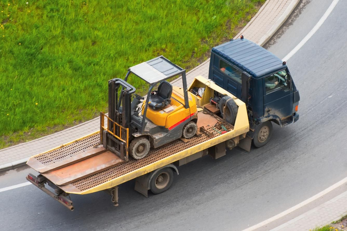 A Tow Truck is Carrying a Forklift on the Back of It — DJ's Tilt Tray Service in Woolgoolga, NSW