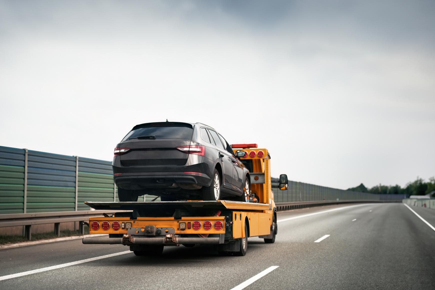 A Tow Truck is Towing a Car on a Highway — DJ's Tilt Tray Service in Sawtell, NSW