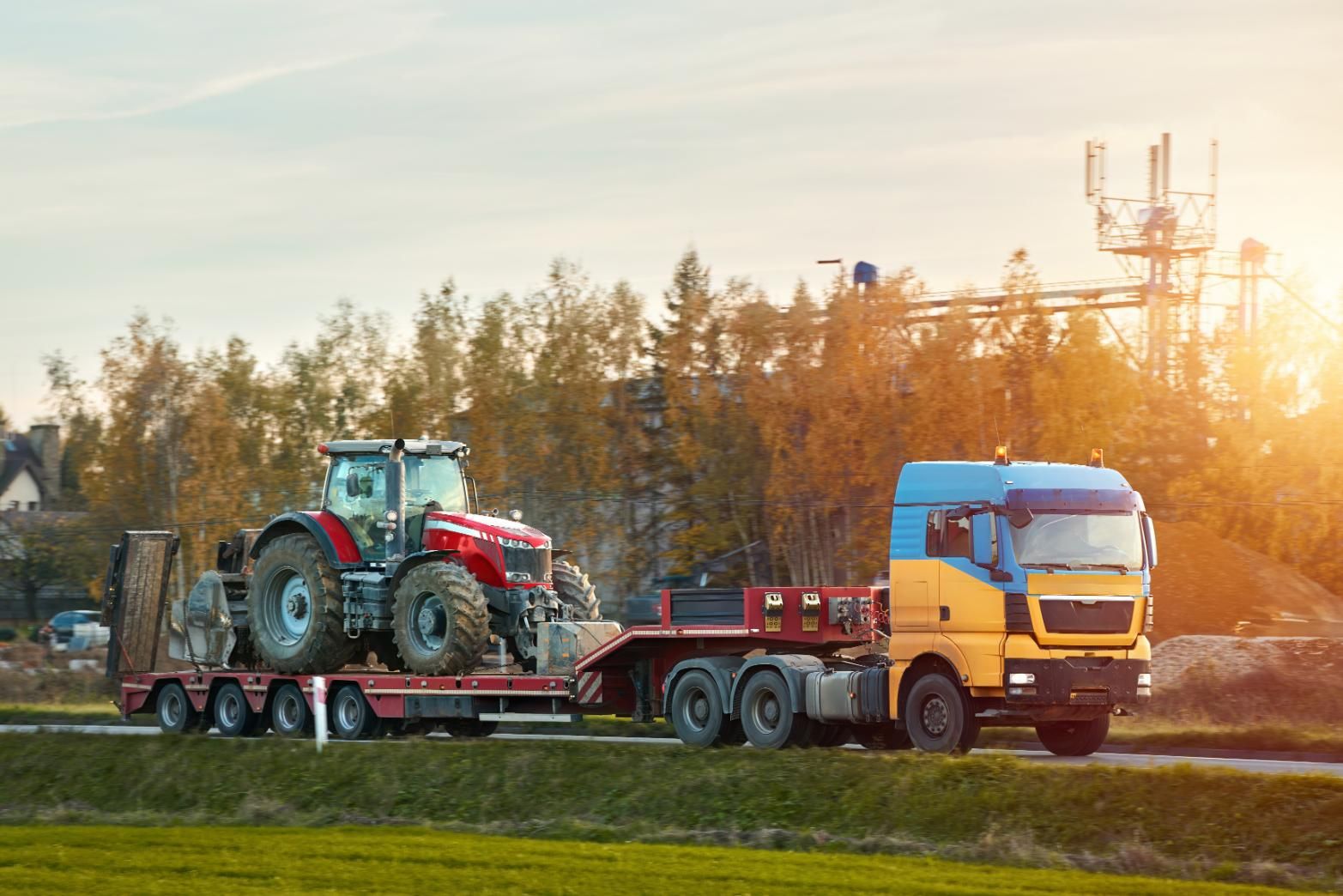 A Semi Truck is Carrying a Red Tractor on a Trailer — DJ's Tilt Tray Service in Urunga, NSW