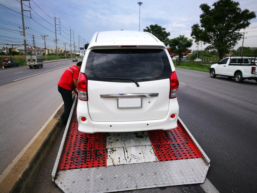 A White Van is Being Towed by a Tow Truck — DJ's Tilt Tray Service in Nambucca Heads, NSW