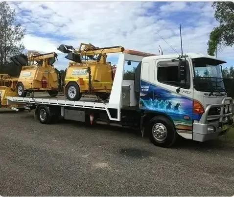 A Tow Truck With a Flatbed is Parked in a Parking Lot — DJ's Tilt Tray Service in Coffs Harbour, NSW