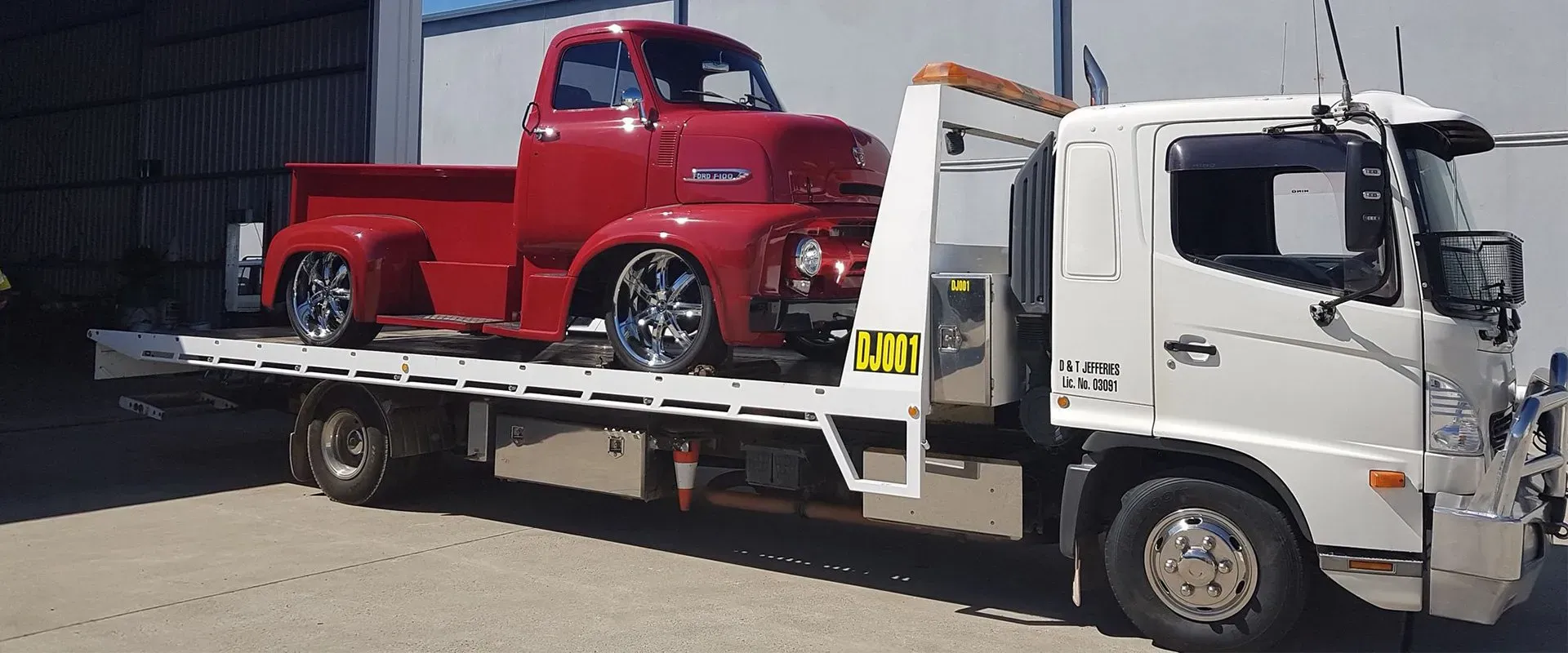 A Red Truck is Being Towed by a White Tow Truck — DJ's Tilt Tray Service in Urunga, NSW
