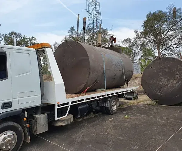A Tow Truck is Carrying a Large Tank on the Back of It — DJ's Tilt Tray Service in Coffs Harbour, NSW