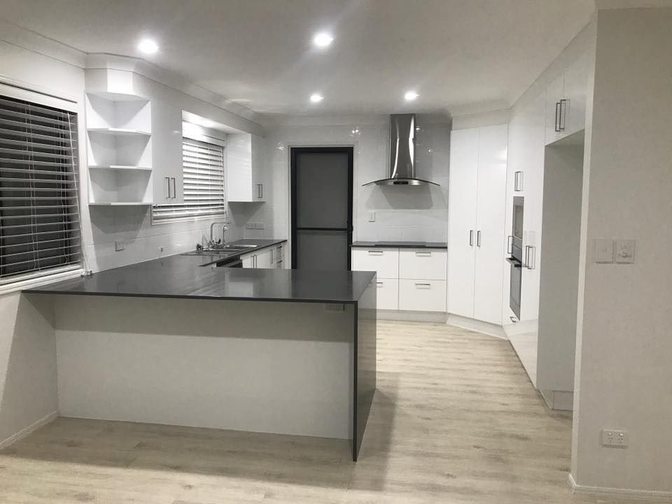 A Kitchen With White Cabinets And A Black Counter Top — O'Donnell Cabinetmaking in Kawana, QLD
