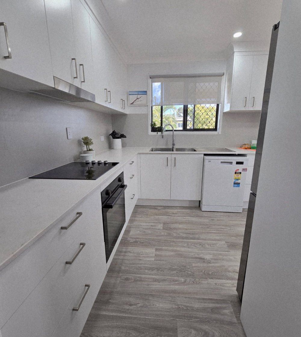 A Kitchen With White Cabinets And A Black Stove Top Oven — O'Donnell Cabinetmaking in Kawana, QLD