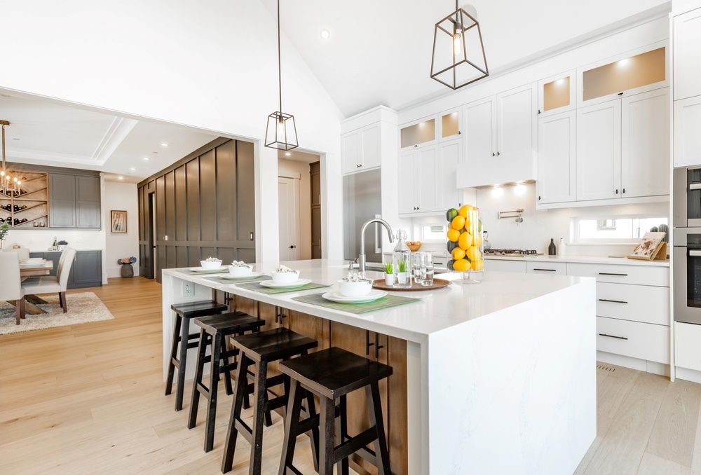 A Kitchen With White Cabinets And A Large Island With Stools — O'Donnell Cabinetmaking in Yeppoon, QLD