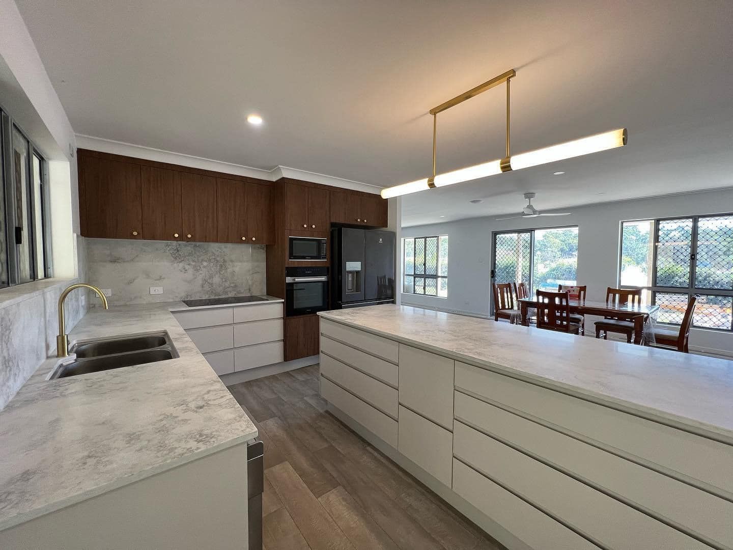 A Kitchen With A Large Island , Sink , Refrigerator , And Dining Area — O'Donnell Cabinetmaking in Kawana, QLD