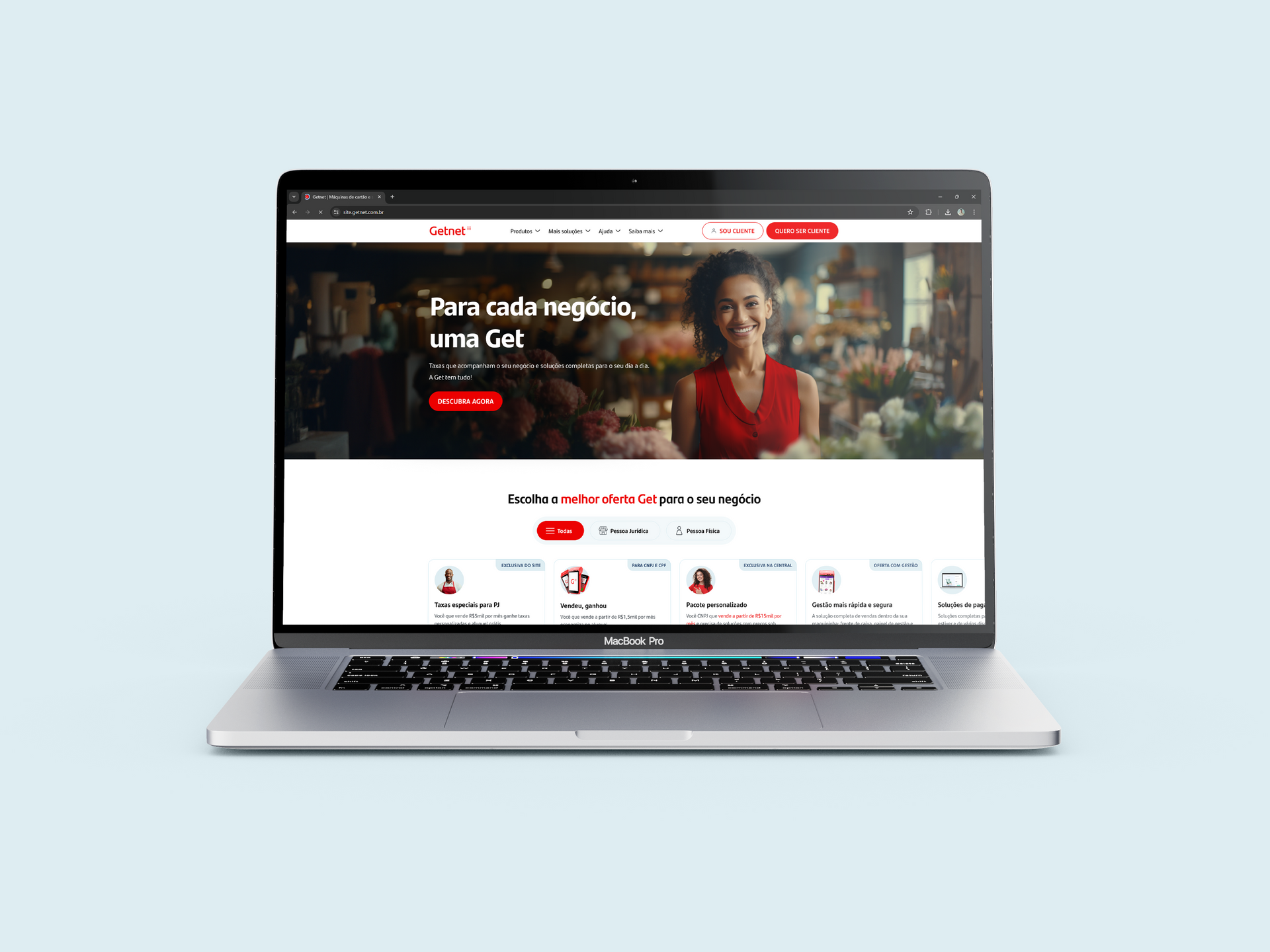 Um laptop está aberto em um site com uma mulher de vestido vermelho na tela.