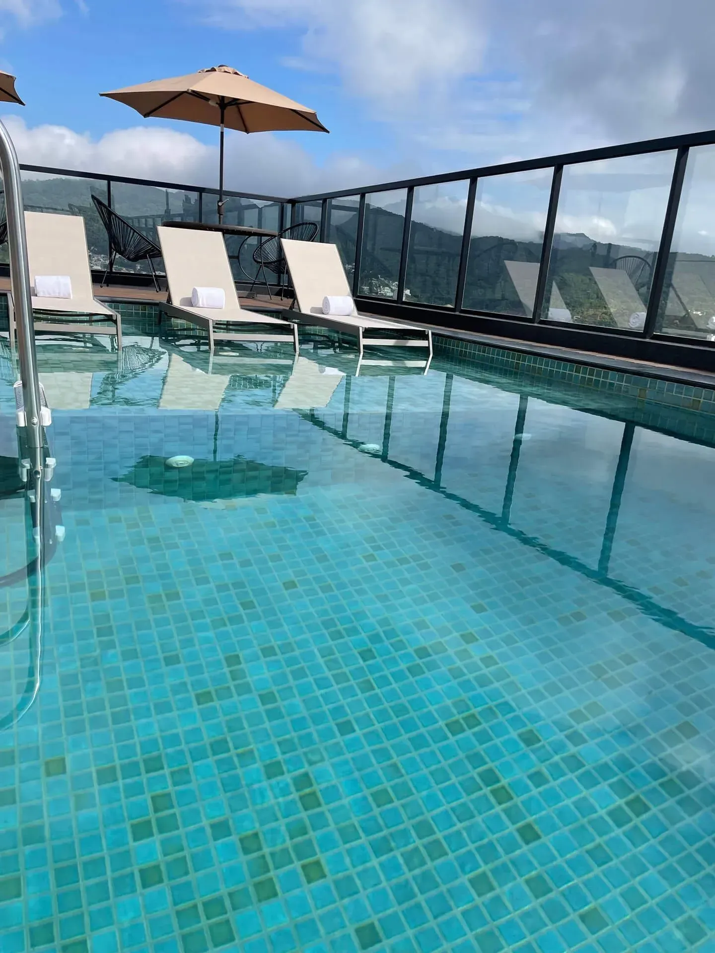 Uma grande piscina cercada por cadeiras e guarda-sóis em uma varanda.