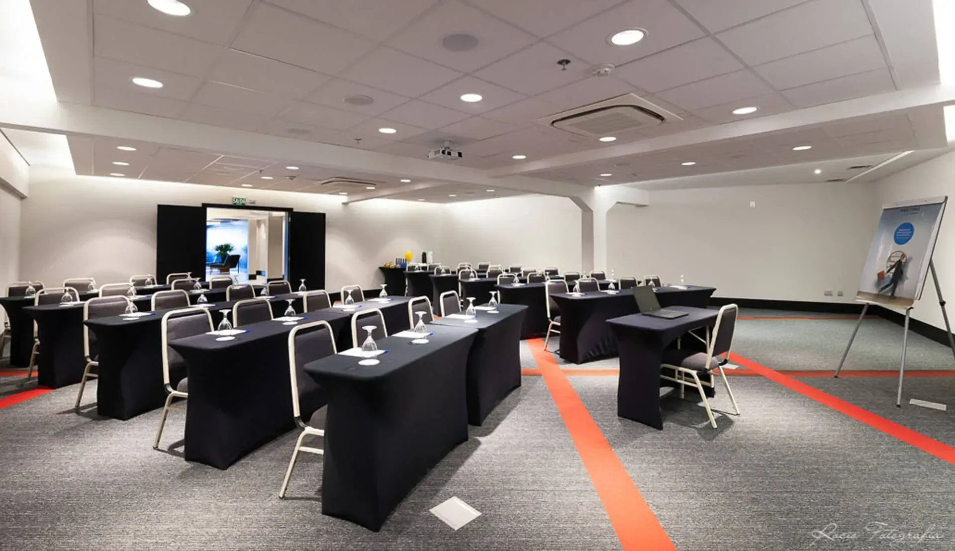 Uma grande sala de conferências com mesas e cadeiras preparadas para uma reunião.