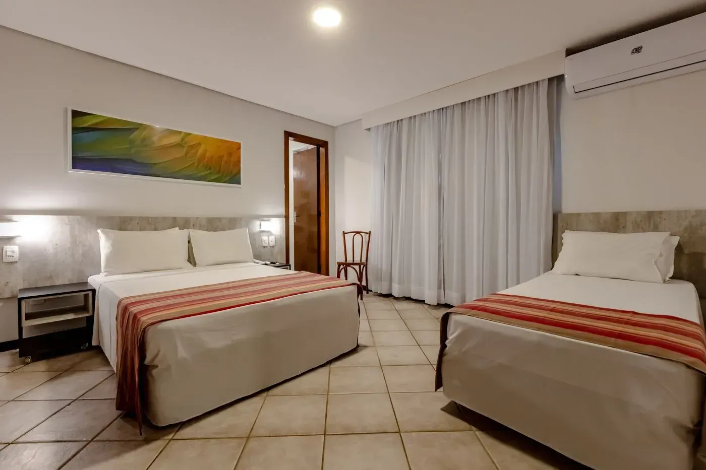 Um quarto de hotel com duas camas e uma cadeira.