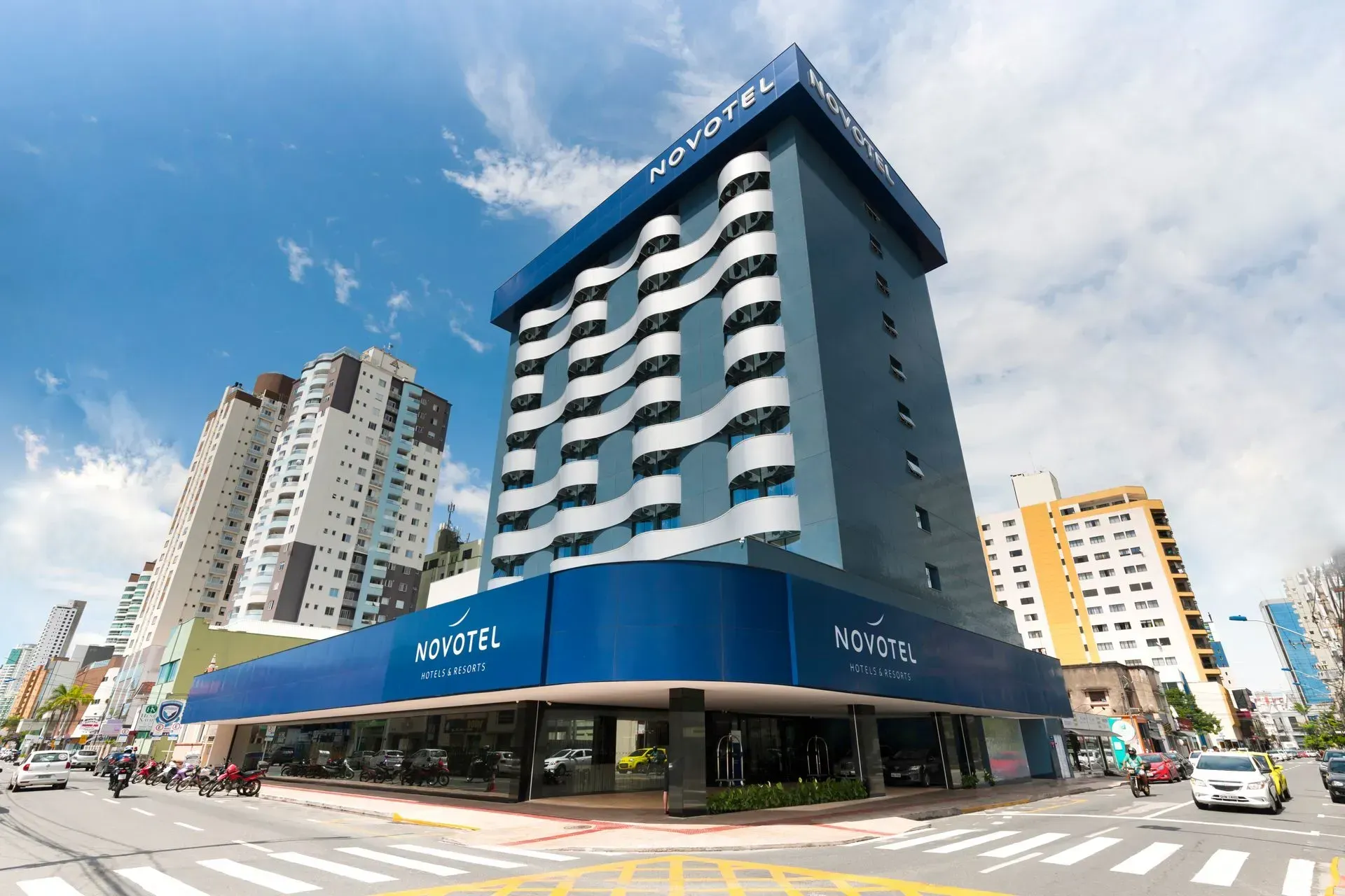 Um grande edifício azul e branco está situado na esquina de uma rua da cidade.