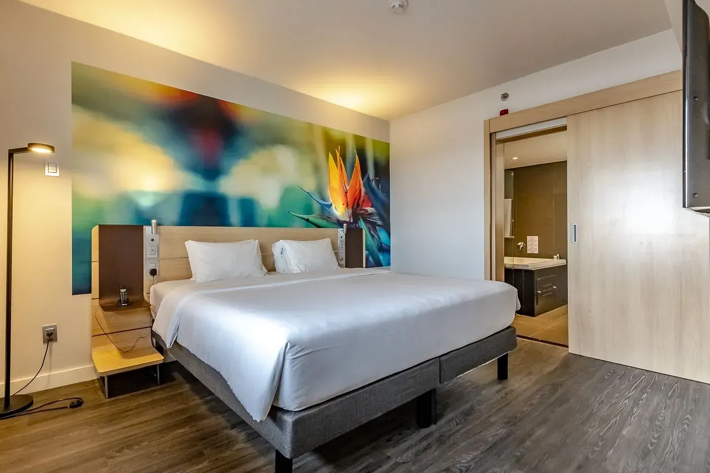 Um quarto de hotel com uma cama king size e uma pintura na parede.