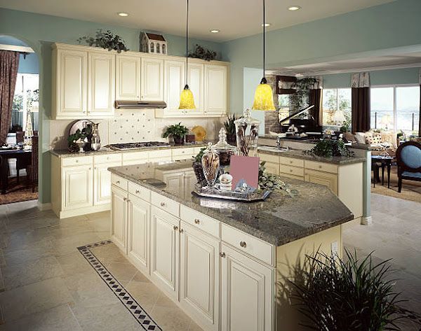 Bright modern kitchen with cream cabinets, granite island, and yellow pendant lights opening to a dining room