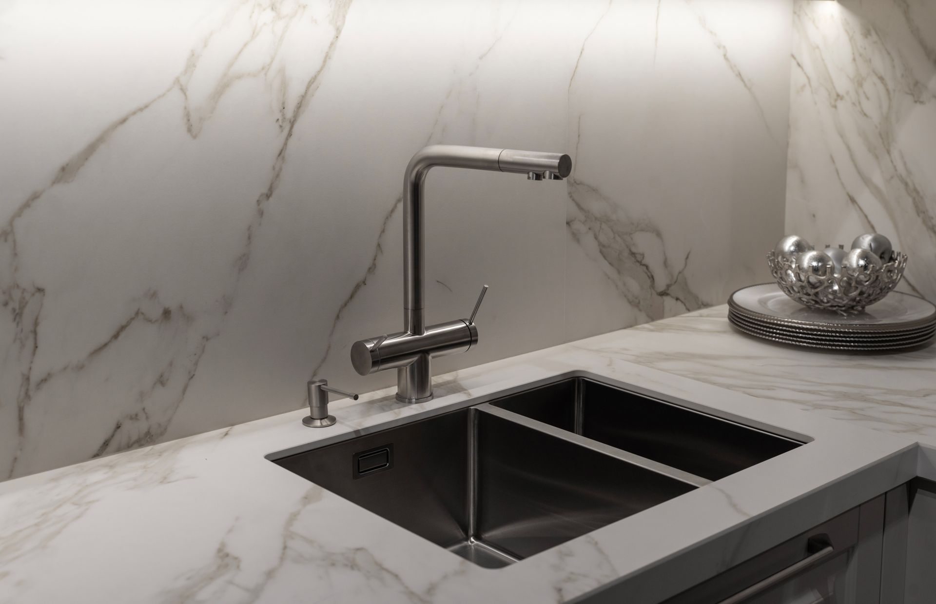Modern kitchen sink with chrome faucet and marble countertops and backsplash