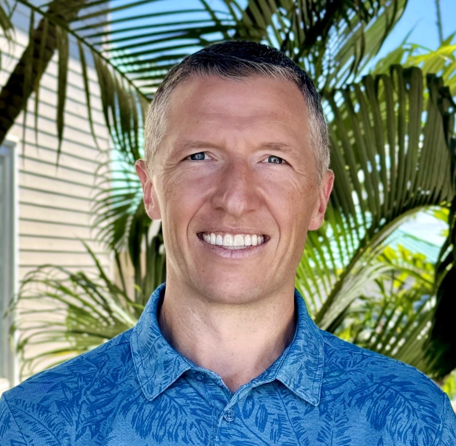 A man in a suit and blue shirt is smiling for the camera.