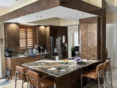 A kitchen with a large island and stools and a laptop on the counter.