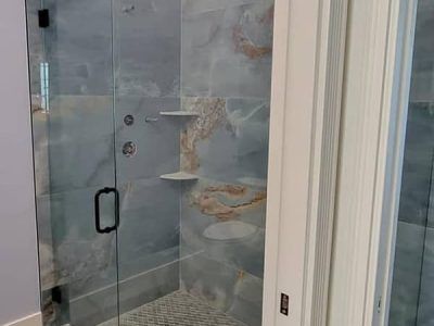A bathroom with a walk in shower with a glass door.