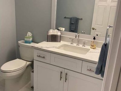 A bathroom with a toilet , sink , and mirror.
