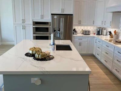 A kitchen with white cabinets and a large island with pumpkins on it.