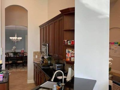 A kitchen with a sink , microwave , and a dining room in the background.