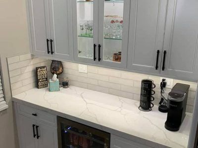 A kitchen with white cabinets , a refrigerator , and a coffee maker.