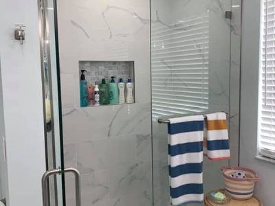A bathroom with a walk in shower and a window.
