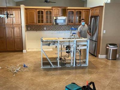 A man wearing a mask is standing in a kitchen.