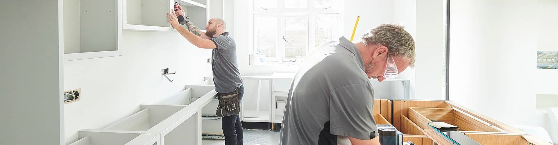 A couple of men are working on a kitchen.