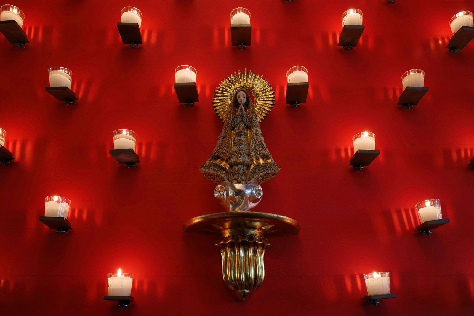 Pared del restaurante  azulísimo con velas encendidas sobre una pared roja.