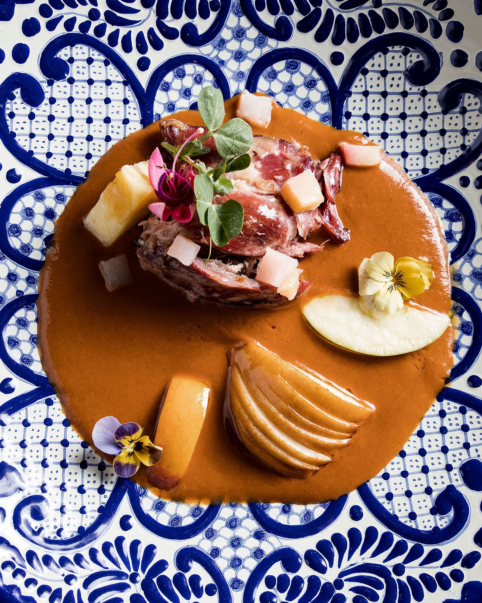 Postre gourmet con guarnición de fruta y pera en rodajas.