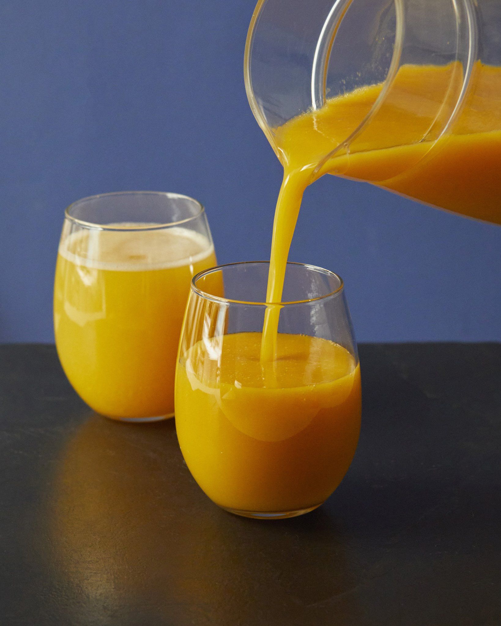 Se vierte zumo de naranja en un vaso, con otro vaso de zumo al lado.