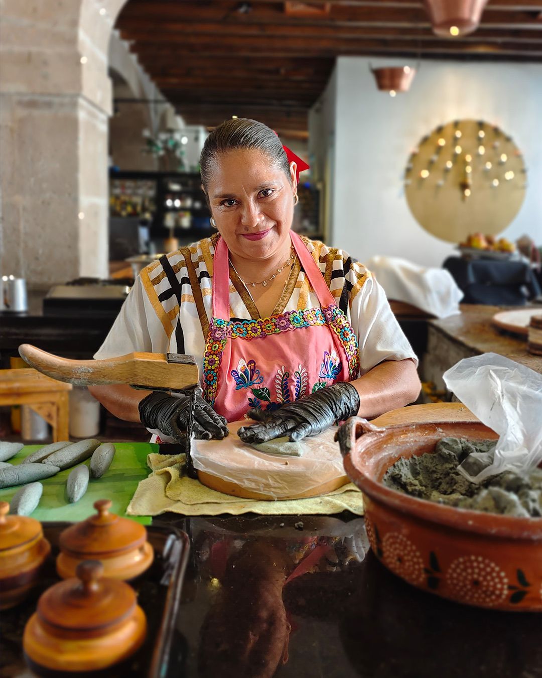 Vendedora con delantal colorido mostrando cuencos de madera de restaurante Azulísimo