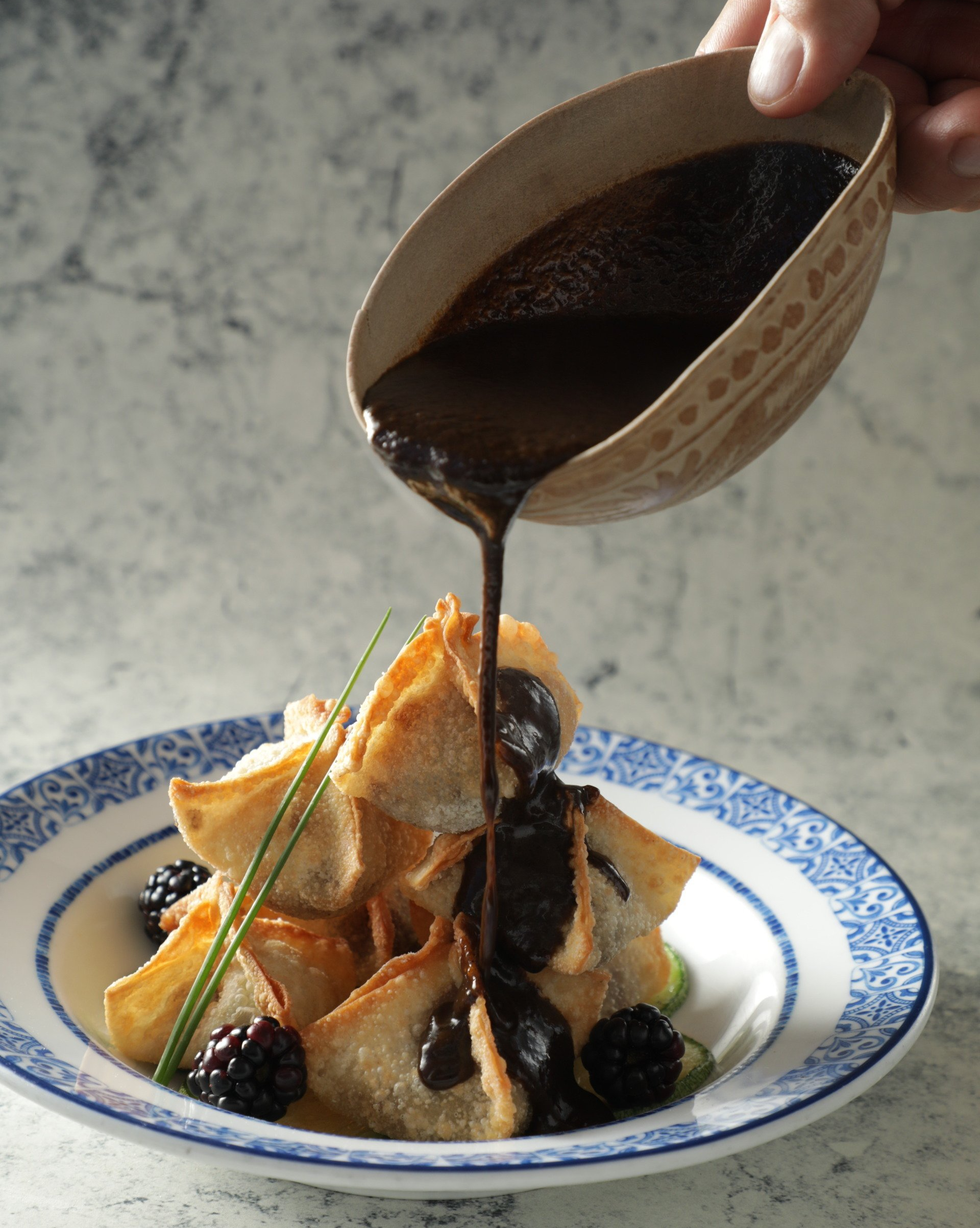Salsa oscura vertida sobre un postre en un plato azul y blanco.