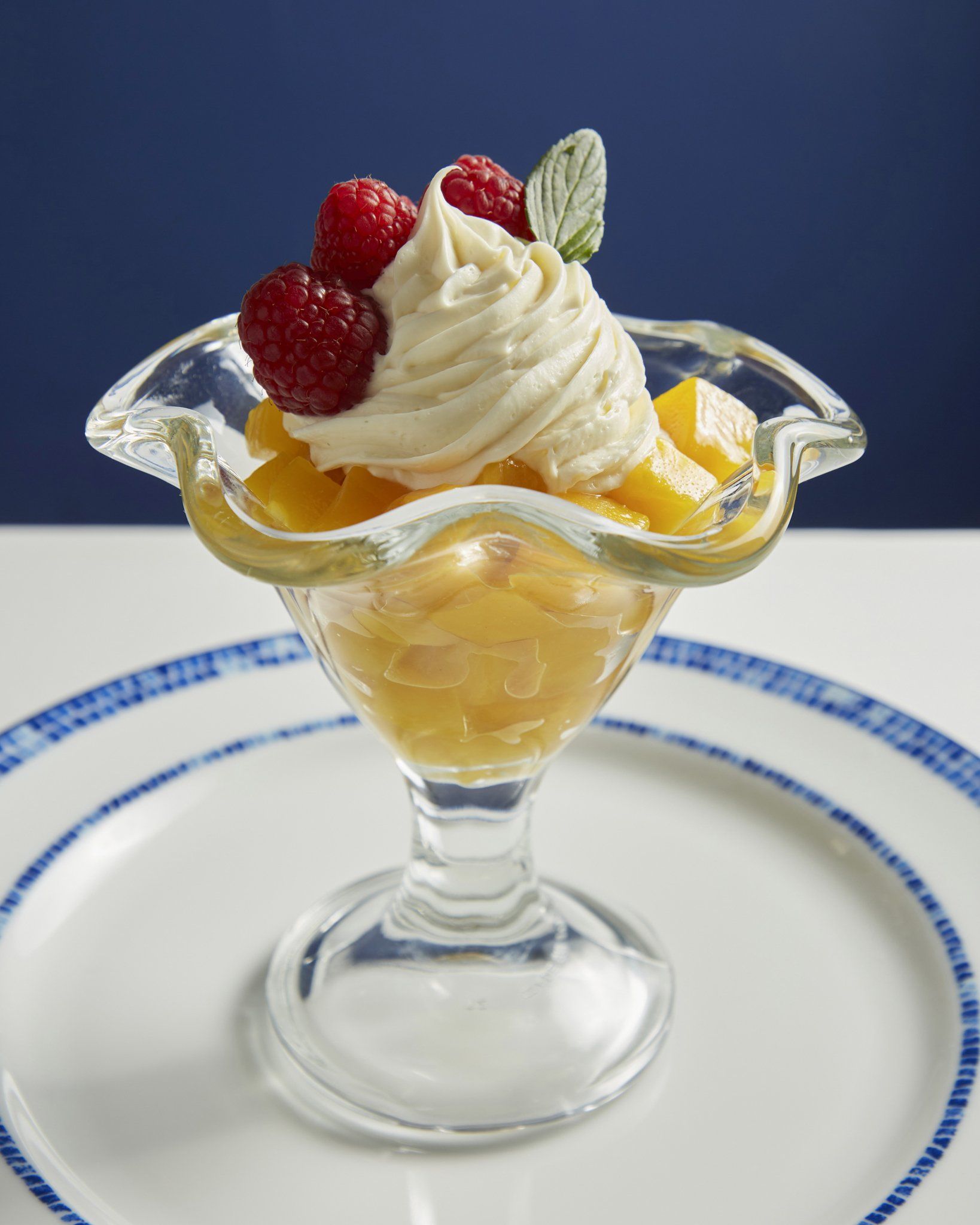 Parfait de crema batida con fresas en un plato de postre de vidrio transparente.
