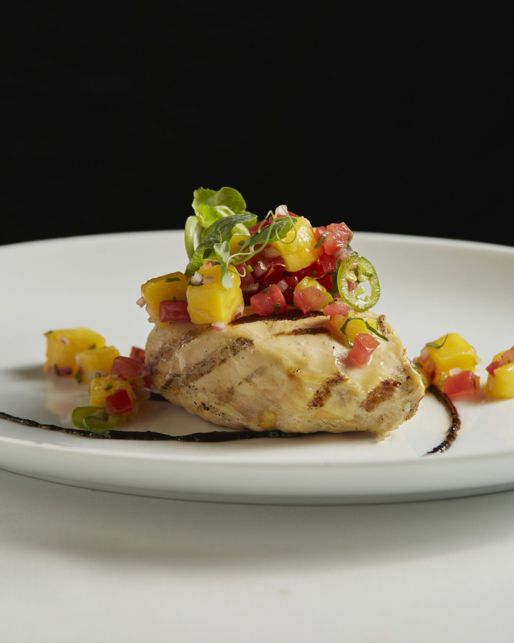 Pechuga de pollo a la parrilla cubierta con coloridas verduras picadas y salsa 