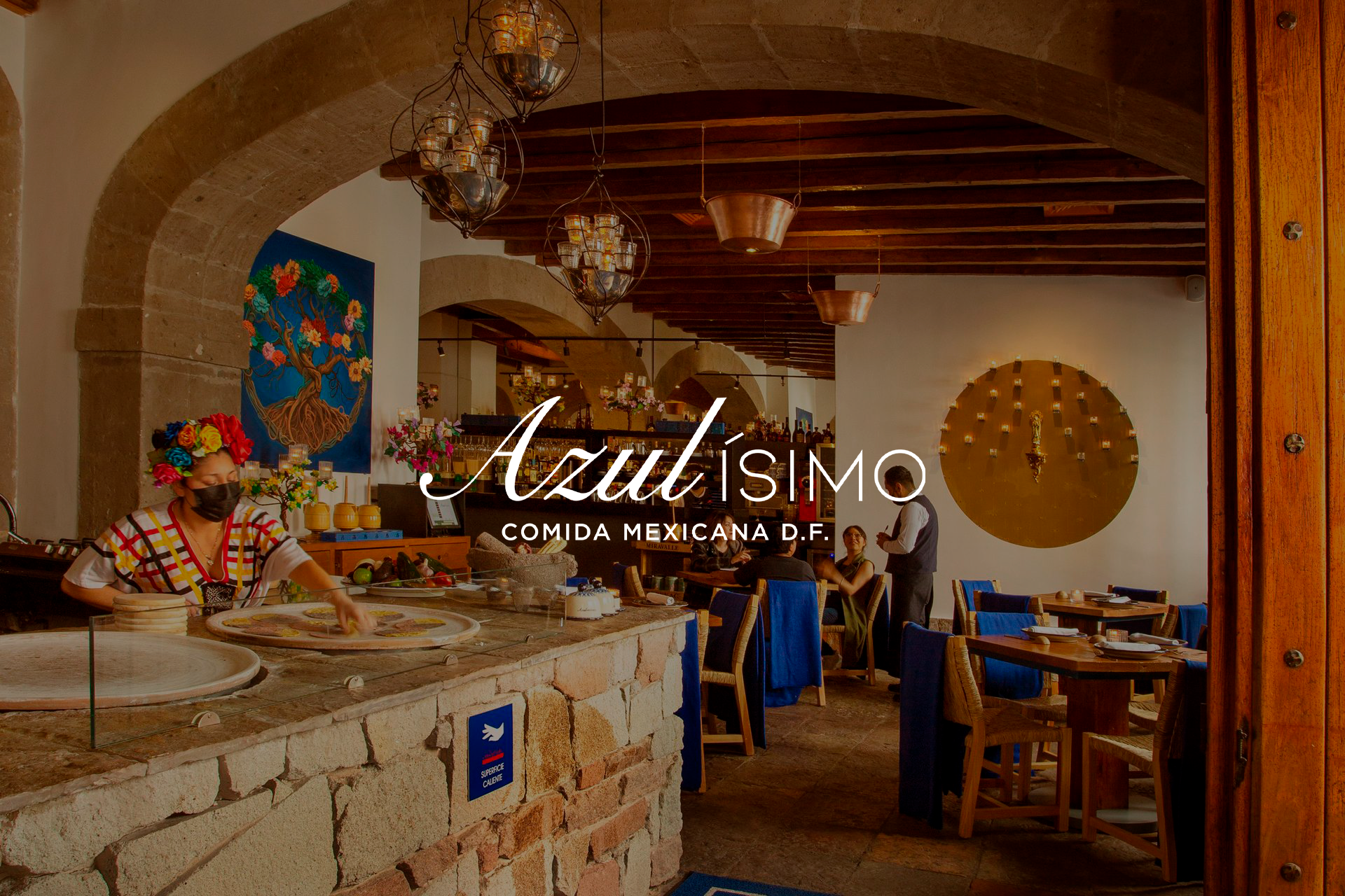 Interior cálido y rústico del restaurante con arco de piedra, vigas de madera, mesas y letrero