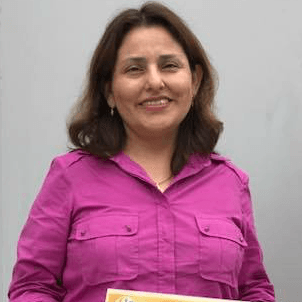 Una mujer con una camisa morada sostiene un libro y sonríe.