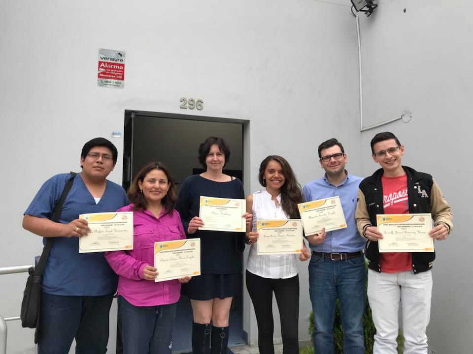 Un grupo de personas se encuentra frente a un edificio sosteniendo certificados.