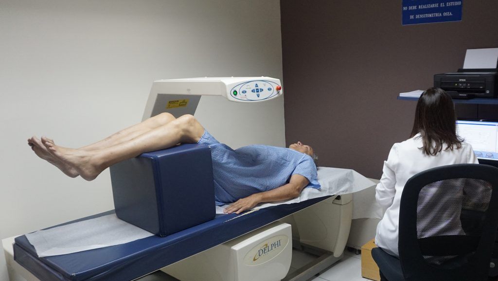 Un hombre está acostado en una cama mientras un médico lo observa.