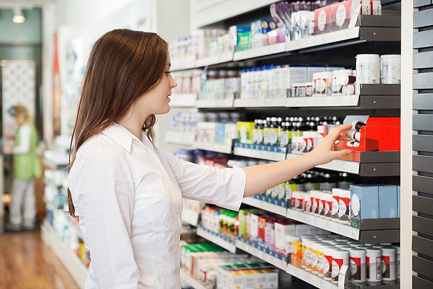 Una mujer está mirando un frasco de medicina en una farmacia.