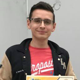 Un joven que lleva gafas y una camisa roja sostiene un certificado.